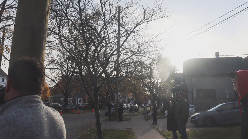 A crowd of people look off-camera to the church being demolished.